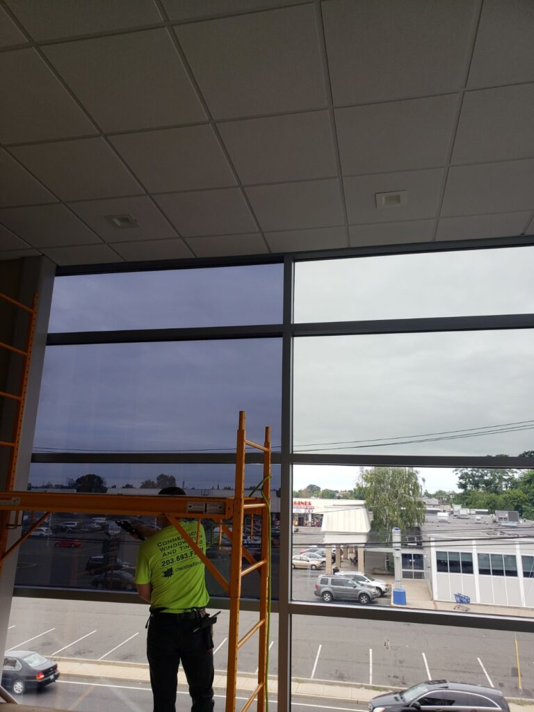 Man installing windows in office building looking out onto street